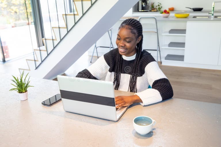 Freelancer working on a laptop at home with coffee, representing writing, graphic design, and digital tech services, expressing side hustles that work well in a tough economy.